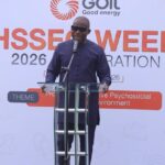 Man in a dark purple outfit speaks at a transparent podium on a stage, with a banner reading 'HSSE WEEK 2026' and the 'Goil Good energy' logo in the background.