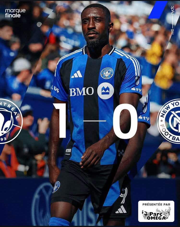 Soccer player in blue and black striped jersey walking on the field with a bold 1–0 score overlay, crowd in the background, team crests and sponsor logos visible.