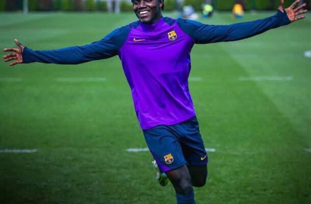 Footballer in a purple FC Barcelona training kit celebrates with arms outstretched on a grassy field, a 'COMUNICAT MÈDIC' banner above.