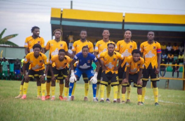 Soccer team in yellow jerseys lined up for a pre-match photo, goalkeeper in blue at center.