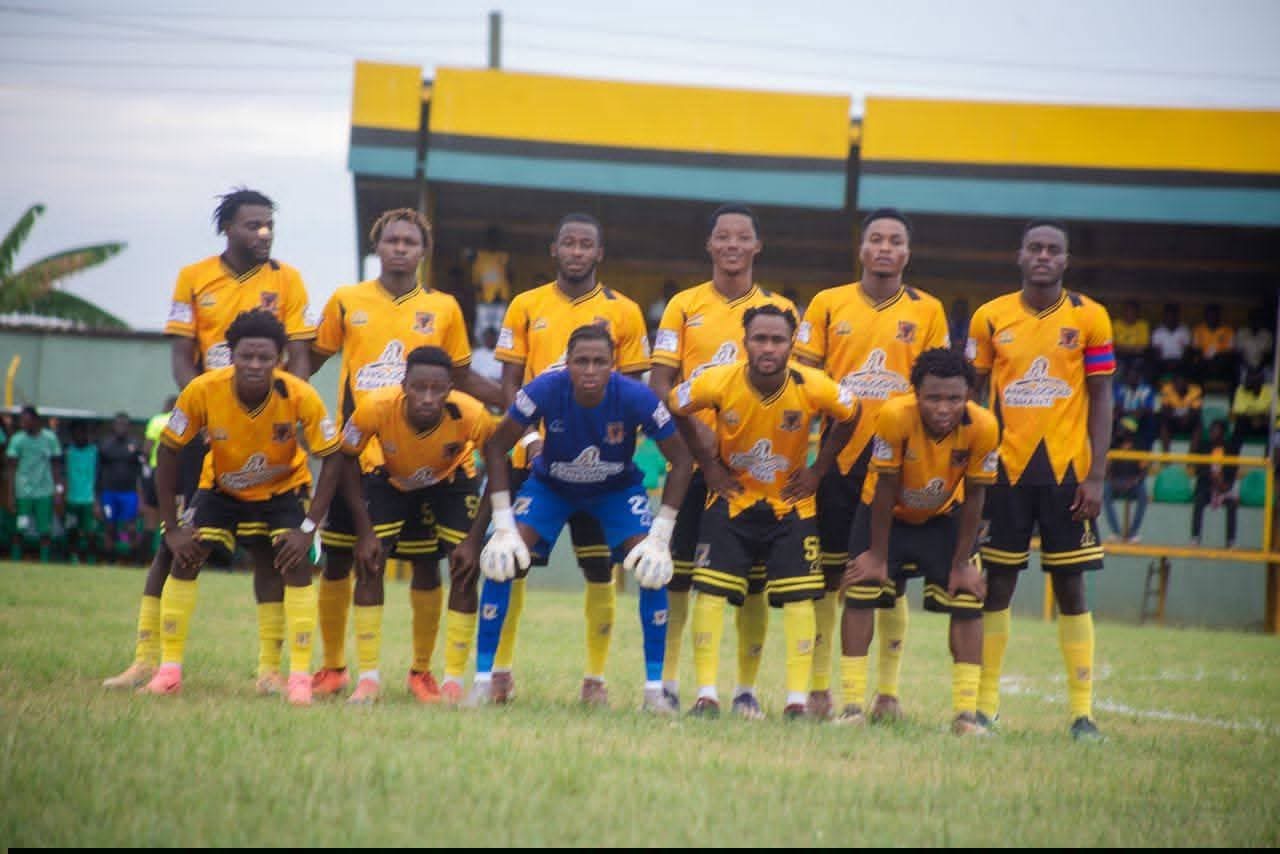 Soccer team in yellow jerseys lined up for a pre-match photo, goalkeeper in blue at center.