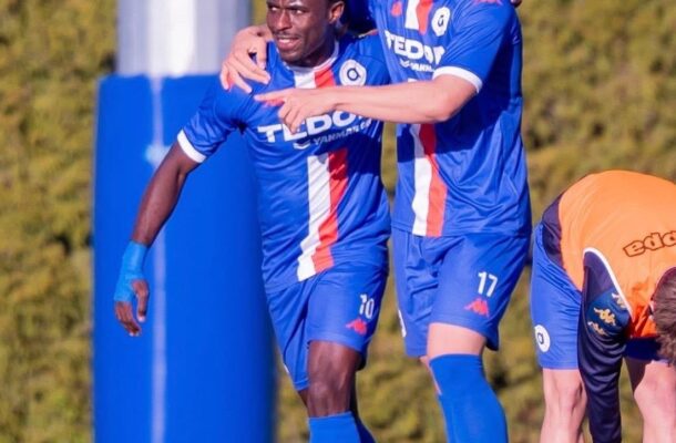 Two soccer players in blue uniforms celebrate together on the field, one with an arm around the other in a joyful moment.