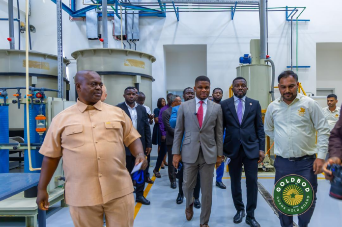 Group of officials on a factory tour walking past large industrial machinery in a processing plant.