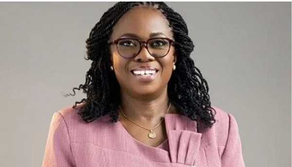 Smiling professional headshot of a woman with glasses and braided hair, wearing a pink blazer.