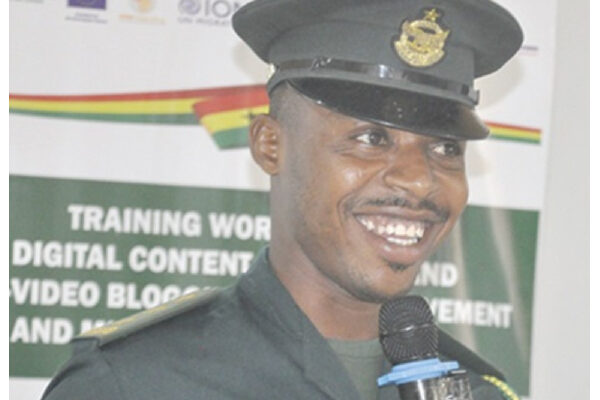 Smiling police officer in uniform speaking into a microphone at a training event.