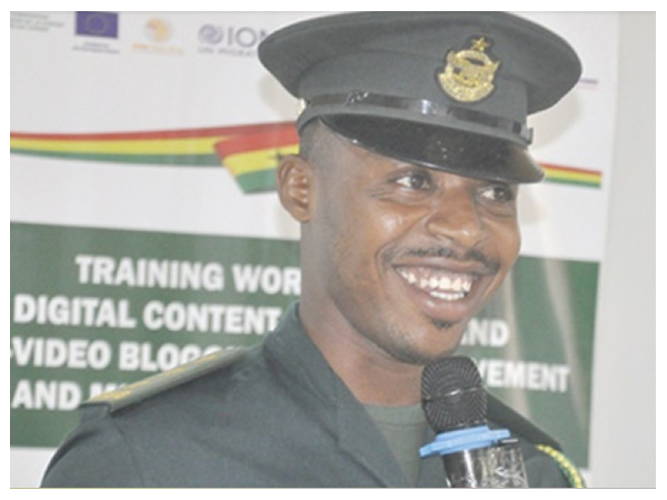 Smiling police officer in uniform speaking into a microphone at a training event.