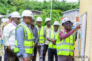 53256075295 | Ghanaguardian.com Group of people in hard hats and high-visibility vests, with one person pointing at a signboard on a construction site.