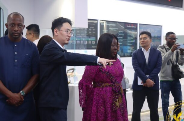 705298703_1379527720869291_5093302074329967242_n-1140x570 | Ghanaguardian.com Presenter in a dark suit points to display screens in a bright showroom as a diverse group watches attentively.