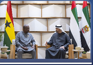 Two men in traditional attire sit in armchairs during a formal meeting, with Ghana and UAE flags behind them.