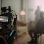 Cinematographer adjusts a camera on a rig with a monitor showing the set in the foreground.