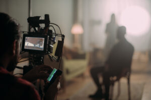 Cinematographer adjusts a camera on a rig with a monitor showing the set in the foreground.