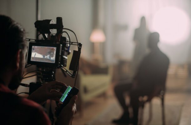 Cinematographer adjusts a camera on a rig with a monitor showing the set in the foreground.