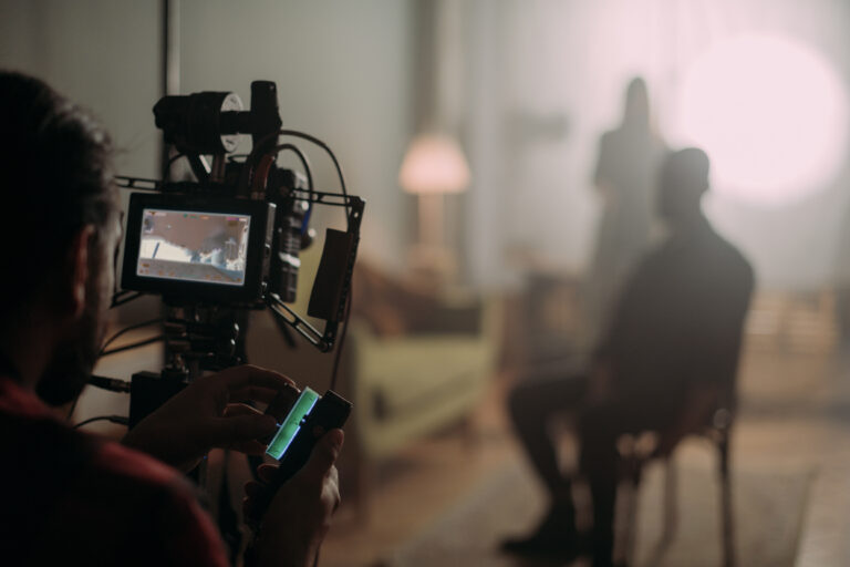 Cinematographer adjusts a camera on a rig with a monitor showing the set in the foreground.