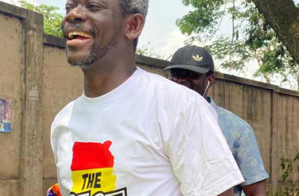 Agya Koo the base | Ghanaguardian.com Joyful man in a white T-shirt with a red-yellow-green flag design and the word THE RISE, outdoors beside a wall, another man in a cap behind him.