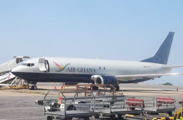 Air Ghana passenger jet parked on the tarmac beside ground support equipment and portable stairs at the gate.