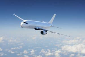 White passenger jet banking in the sky above a sea of clouds, blue clear backdrop
