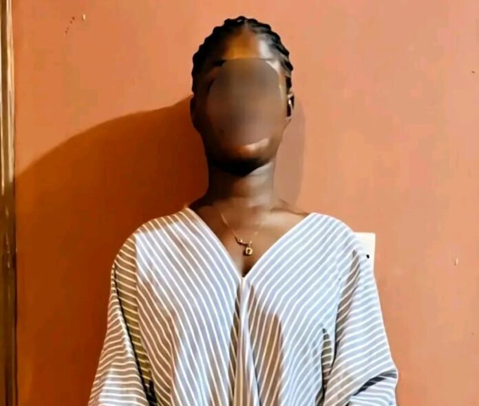 Person with braided hair wearing a striped V-neck top, standing against an orange wall; face blurred for privacy.