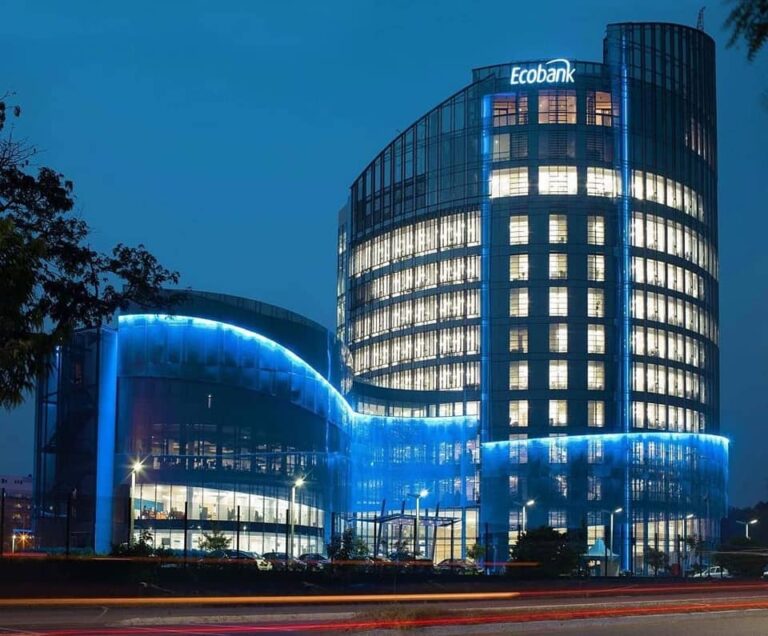 Ecobank office building at night with blue neon lighting along the curved glass facade.