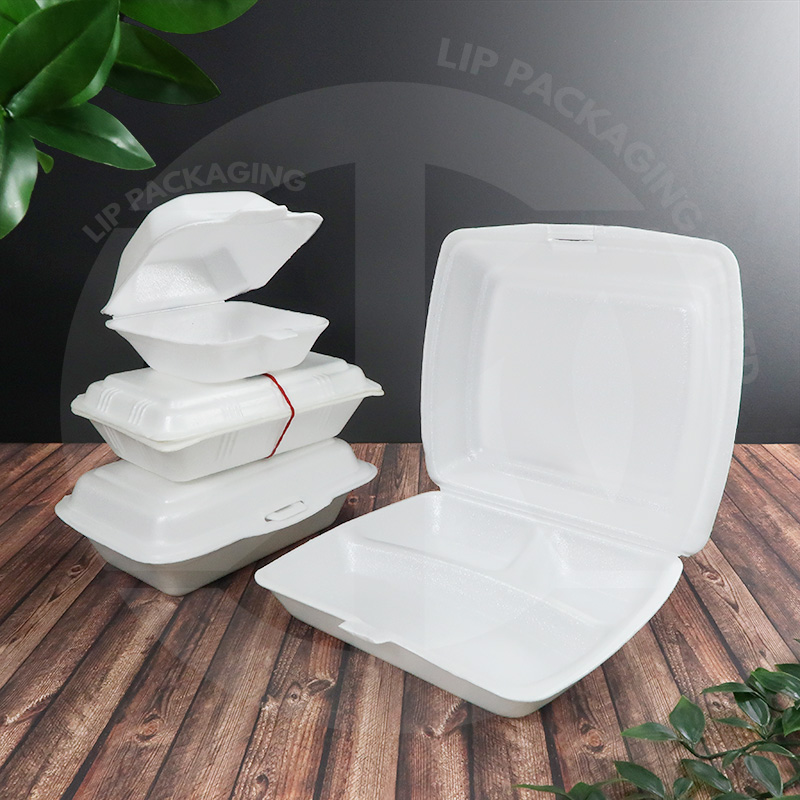 Stack of white disposable takeout containers on a wooden surface, with one open to show the hinged lid and compartments.