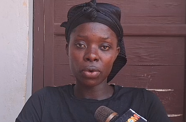 Woman with a black headwrap speaks into a microphone during an interview.