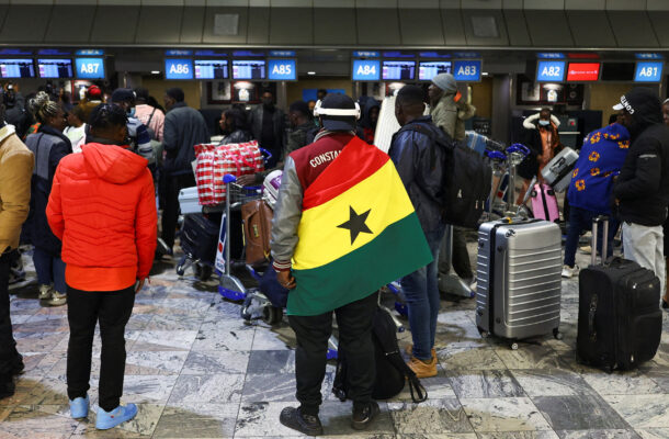 Ghanaians evacuation | Ghanaguardian.com Crowded airport check-in area with travelers and rolling luggage; a man in the center wears the Senegal flag as a cape.