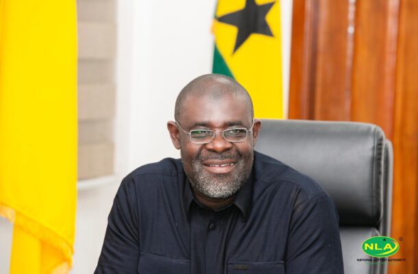 Smiling man with glasses seated at a desk in an office, yellow background and NLA logo in the corner.