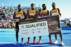 Four Ghanaian sprinters on a blue track hold a large banner that reads 'QUALIFIED' for the World Athletics Championships in Beijing, with the slogan 'From Botswana to Beijing.'