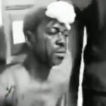 Man shirtless with a towel on his head, eyes closed, seated in a dim room.