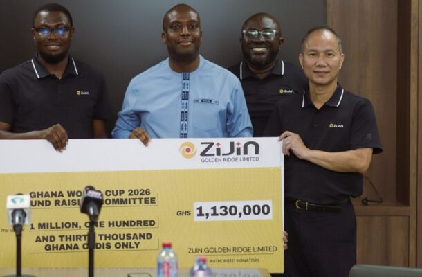 Four men stand behind a large ceremonial cheque from ZiJin Golden Ridge Limited during a press event. The sign shows an amount of GHS 1,130,000 for a Ghana World Cup 2026 fundraiser, with microphones in the foreground.