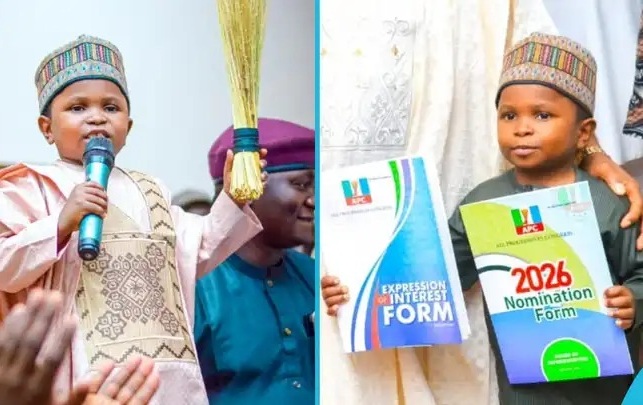 Two boys in traditional attire on stage; one speaks into a microphone, the other holds 2026 nomination and expression of interest forms.
