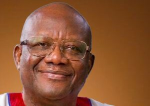 Close-up portrait of a smiling man wearing glasses against a brown background.