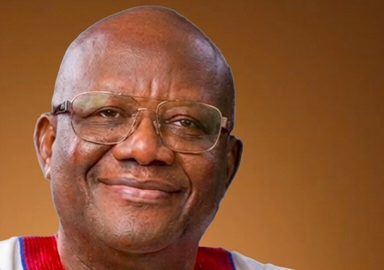 Close-up portrait of a smiling man wearing glasses against a brown background.
