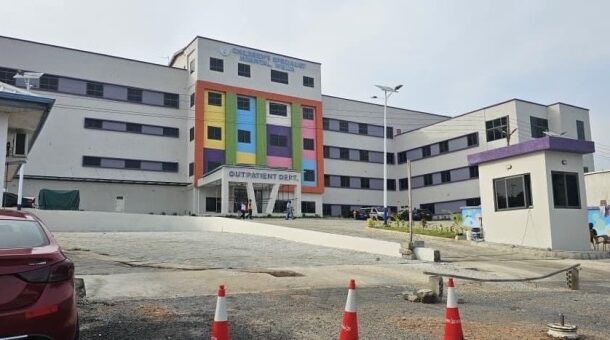 IMG-20260527-WA0022 | Ghanaguardian.com Colorful hospital building with an outpatient entrance, parked car in foreground and orange traffic cones on a paved lot.