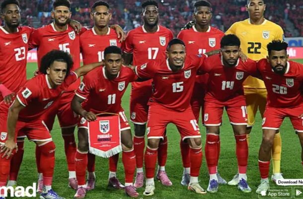 Panama national football team posing for a group photo on the pitch, players in red kits with white numbers and a yellow-clad goalkeeper in back.