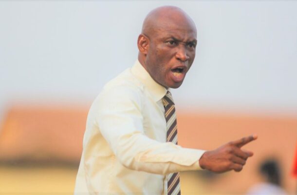 Angry bald man in a pale dress shirt and striped tie shouting and pointing outdoors.
