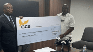 Two men in a conference room hold a large ceremonial check from GCB Bank for two million dollars.