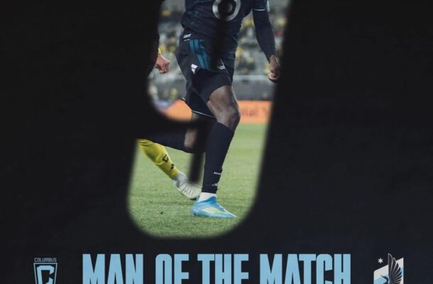 Soccer player in a dark kit with a white headband running on a field, seen through a goal opening, with large 'MAN OF THE MATCH' text below.