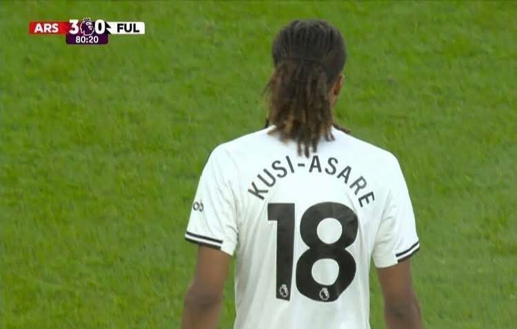 Back view of a soccer player in a white jersey with 'KUSI-ASARE' and the number 18; green field and a scoreboard showing Arsenal 3, Ful 0.