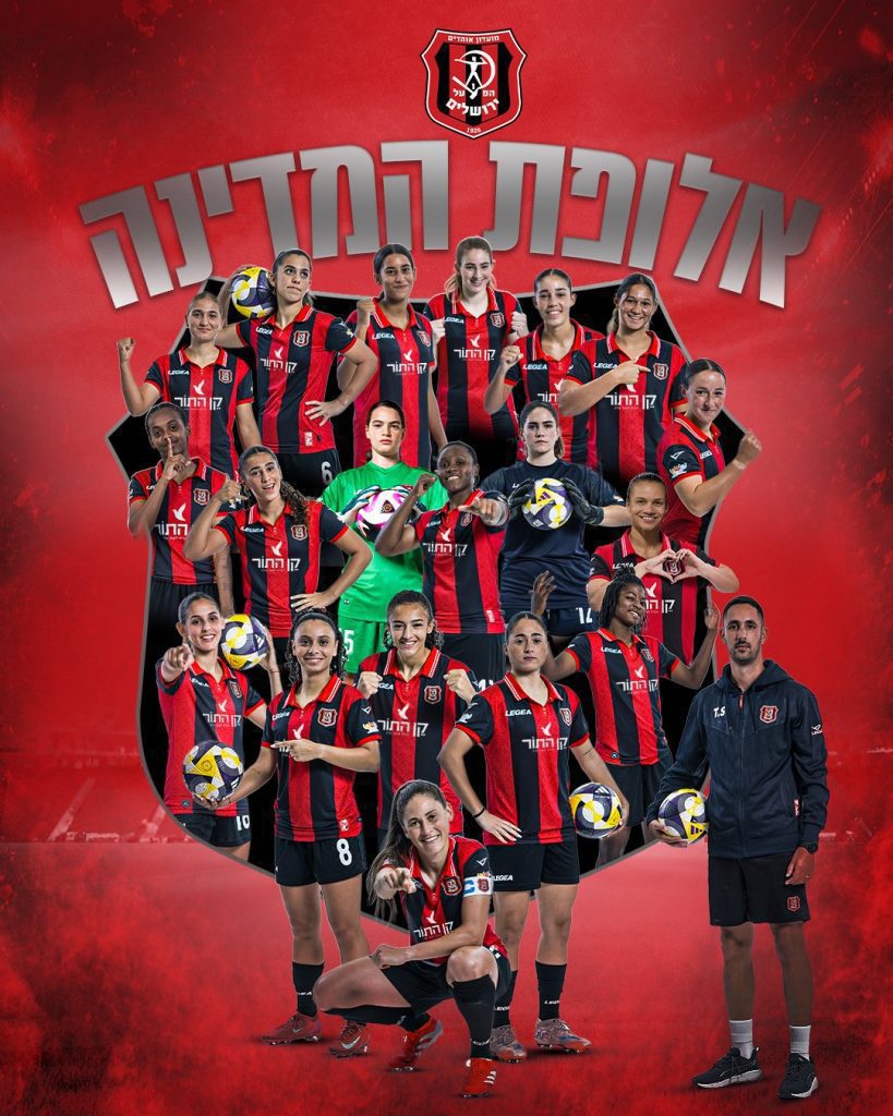 Group portrait of a women's volleyball team in red-and-black jerseys posing together; several players hold volleyballs, with a coach on the right, set against a red background with large Hebrew text that reads 'State Champion'.