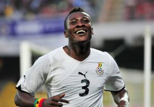 Soccer player in a white jersey with the number 3 celebrates with a smile on the field.