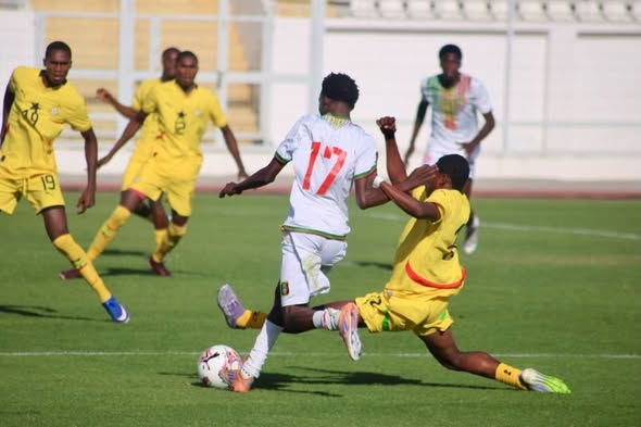 Soccer match action: a white‑jersey player (#17) dribbles past a yellow‑shirt defender during a slide tackle.