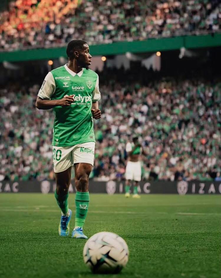 Soccer player in a green and white kit on a packed stadium field, ball at his feet before a kickoff or pass.