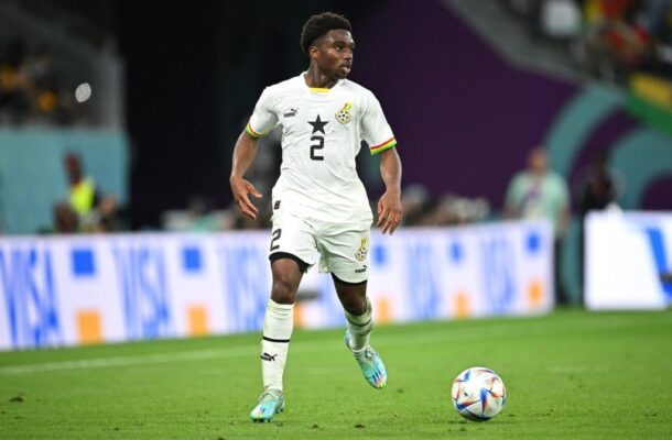Ghana national team player in a white kit with number 2 dribbling the ball on a green pitch during a match.