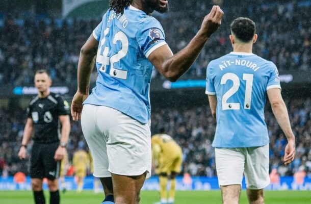 Two Manchester City players celebrate on a rainy pitch, foreground player raising a fist (#42).
