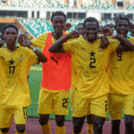 Group of football players in yellow jerseys celebrating with arms around each other on the field.