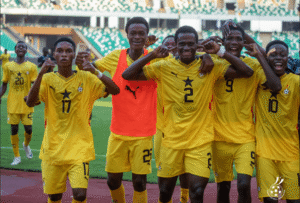Group of football players in yellow jerseys celebrating with arms around each other on the field.