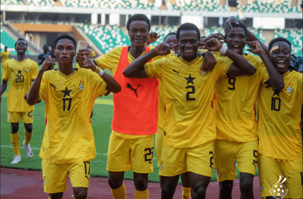 Group of football players in yellow jerseys celebrating with arms around each other on the field.