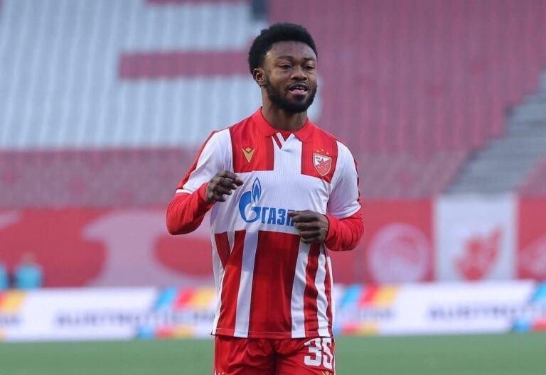 Soccer player in red-and-white striped jersey warming up on a stadium field, number 35 visible on shorts