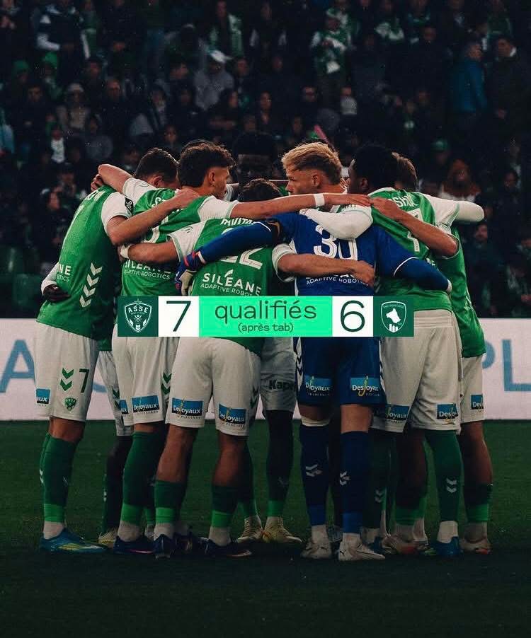 Soccer players in green jerseys form a huddle on the field after the match; the scoreboard shows 7–6 in favor of the qualifiers.
