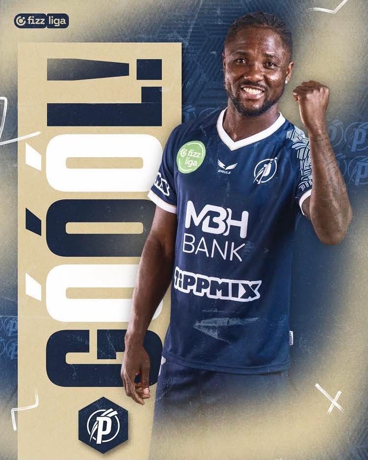 Male soccer player in a blue jersey raising his fist in celebration; sponsor logos MBH Bank and PPMIX visible on his shirt with a large graphic background.